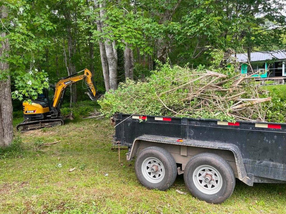 Excavator clearing branches and vegetation